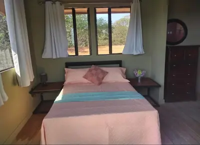 a bedroom with a large bed with two windows at Fruta mango # 3 in Playa Guacalillo
