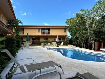 a swimming pool with chairs and a house at Refugio de paz in Jacó