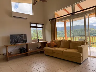 a living room with a couch and some windows at Refugio de paz in Jacó