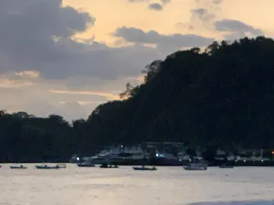 a group of boats on the water in front of a mountain at Refugio de paz in Jacó