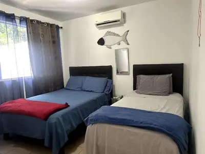 a bedroom with two beds and a fish on the wall at Herradura casa vacacional in Herradura