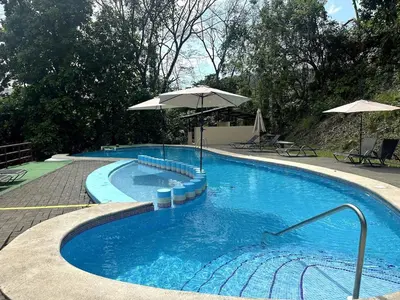 a large blue swimming pool with an umbrella at Herradura casa vacacional in Herradura