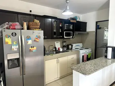a kitchen with a stainless steel refrigerator and white cabinets at Herradura casa vacacional in Herradura