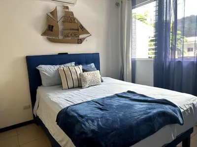 a bed with a blue headboard in a bedroom at Herradura casa vacacional in Herradura