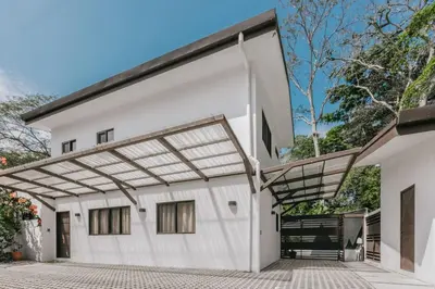 a white building with a pergola on it at Casa Luna in Punta Leona