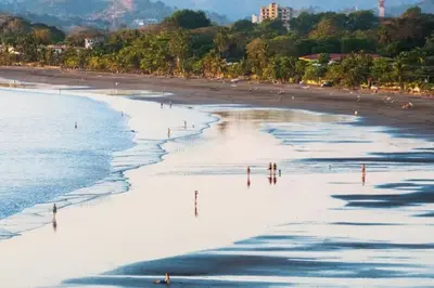 a beach with a bunch of people walking on the sand at . 5 min Walking Beach Jaco Apartment in Jacó