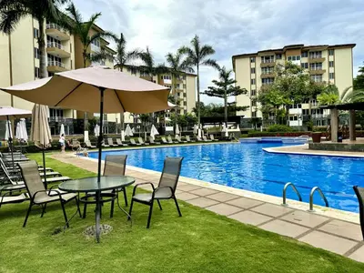 a table and chairs with an umbrella next to a pool at . 5 min Walking Beach Jaco Apartment in Jacó