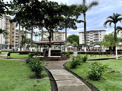 a park with a gazebo and palm trees and buildings at . 5 min Walking Beach Jaco Apartment in Jacó