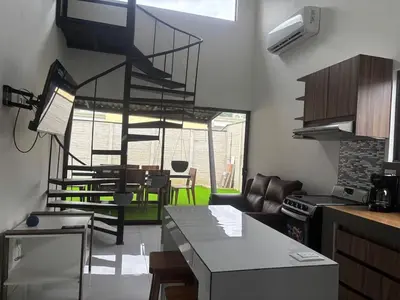 a kitchen and living room with a spiral staircase at Casa Arenas in Herradura