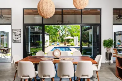 a dining room with a wooden table and white chairs at .Lujosa casa en Hacienda Pinilla in Tamarindo