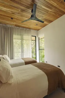 two beds in a bedroom with a ceiling fan at CASA TUCAN , New House with Pool in Paradise, jungle view in Santa Teresa Beach