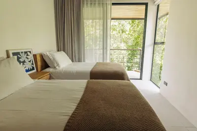 two beds in a hotel room with a window at CASA TUCAN , New House with Pool in Paradise, jungle view in Santa Teresa Beach