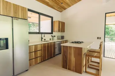 a kitchen with wooden cabinets and a counter top at CASA TUCAN , New House with Pool in Paradise, jungle view in Santa Teresa Beach