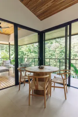 a dining room with a table and chairs and windows at CASA TUCAN , New House with Pool in Paradise, jungle view in Santa Teresa Beach