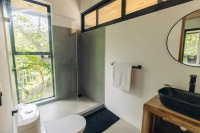a bathroom with a sink and a toilet and a window at CASA TUCAN , New House with Pool in Paradise, jungle view in Santa Teresa Beach