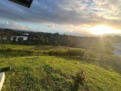 a view of a field of grass with the sun setting at Colina Wilson in Santa Teresa