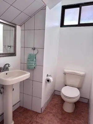 a white bathroom with a toilet and a sink at Coco Daydreamin with a Rooftop Terrace in Coco