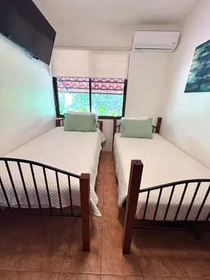 two beds in a small room with two windows at Coco Daydreamin with a Rooftop Terrace in Coco