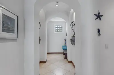 a hallway with white walls and a hallway with surfboards at Stunning Condo with Panoramic Beach, Ocean, and Mountain Views in Playa Flamingo in Playa Flamingo