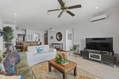 a living room with a white couch and a tv at Stunning Condo with Panoramic Beach, Ocean, and Mountain Views in Playa Flamingo in Playa Flamingo