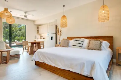 a bedroom with a large white bed and a kitchen at The Bungalows #7 - Boutique Hotel in Flamingo Beach - Ground Level Studio in Playa Flamingo