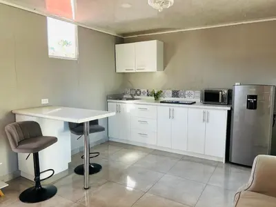 a kitchen with white cabinets and a table and a refrigerator at Apartamento Einoah in Puerto Limón