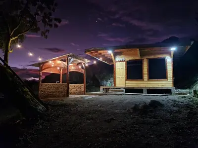 a wooden house with lights on it at night at Hospedaje Jac Cabaña de Campo in Cartago