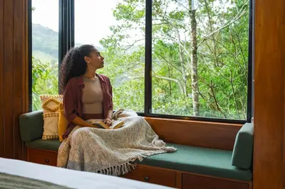 a woman sitting on a bench looking out of a window at NATURAVE HOME - Tiny house with mountain view in Monteverde Costa Rica