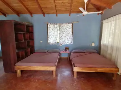 two beds in a room with a window at Cabinas casa las flores in Montezuma