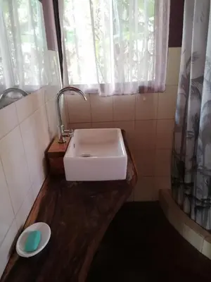 a bathroom with a white sink and a window at Cabinas casa las flores in Montezuma