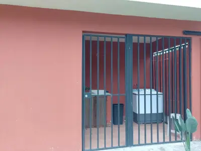 a pink building with a gate with a trash can at Casa Victoria in Orosí