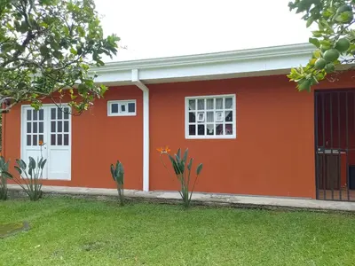 a red house with white windows and a yard at Casa Victoria in Orosí