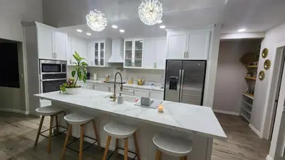 a kitchen with white cabinets and a large island with bar stools at Beautiful and cozy home in Alajuela City