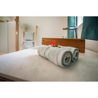a bed with two towels and a flower on it at Drift Away Lodge CR in Santa Cruz