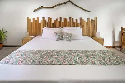 a bedroom with a large white bed with a wooden headboard at Drift Away Lodge CR in Santa Cruz