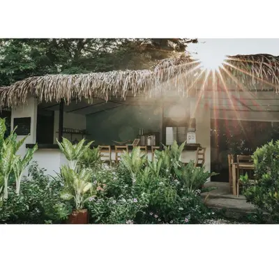 a house with a thatched roof with the sun shining at Drift Away Lodge CR in Santa Cruz
