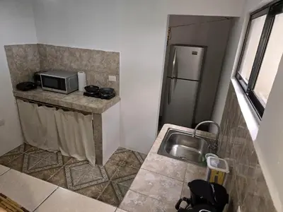 a small kitchen with a sink and a microwave at Casa Rosa - Beach Front in Tortuguero