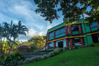 a building on a hill with trees and grass at Lake Arenal Hotel, Brewery & Farm in Tilarán