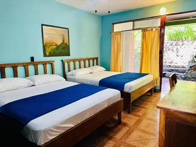 two beds in a room with blue walls and a window at Lake Arenal Hotel, Brewery & Farm in Tilarán