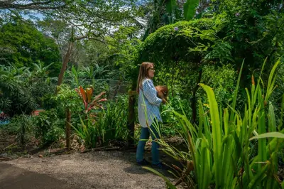 a woman holding a teddy bear in a garden at Lake Arenal Hotel, Brewery & Farm in Tilarán