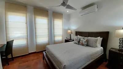 a bedroom with a bed and a desk and two windows at Villa Estrellas - Stunning Ocean-Views, Potrero, spacious 4 BR Villa in Potrero