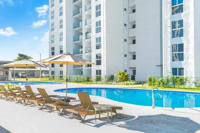 a swimming pool with chairs and an umbrella and a building at 0905 Viva Jaco in Jacó