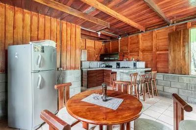 a kitchen with a table and a refrigerator at Gamboa Cabin - Delightful Couples Vacation Cabin in Fortuna