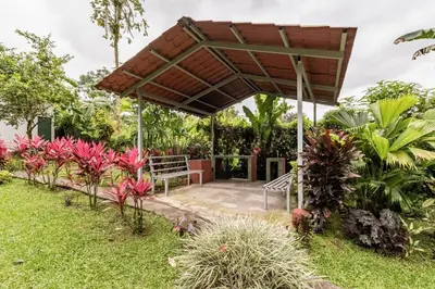 a patio with a wooden canopy in a garden at Gamboa Cabin - Delightful Couples Vacation Cabin in Fortuna