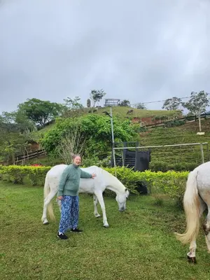 a woman standing in a field with two white horses at Marcana Occidente in San Ramón
