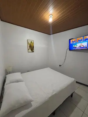 a bedroom with a white bed and a tv at Depa Koral in Puerto Limón