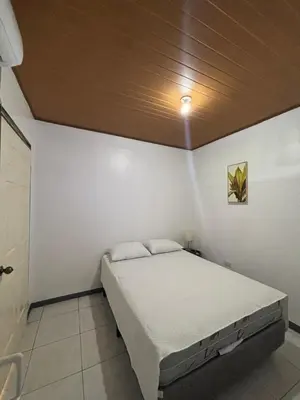 a bedroom with a white bed with a wooden ceiling at Depa Koral in Puerto Limón