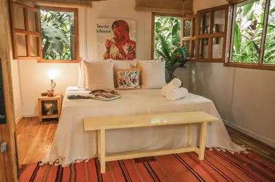 a bedroom with a bed with a bench on it at Surf Casitas - Low Tide Bungalow in Santa Teresa Beach