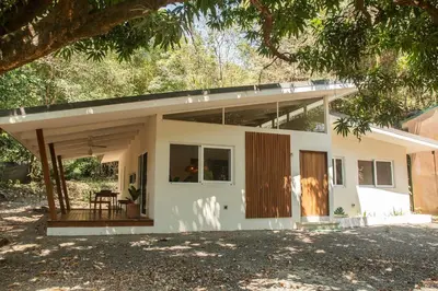 a small white house with a porch at Arroyo Tranquilo - Steps to the Beach in Santa Teresa Beach