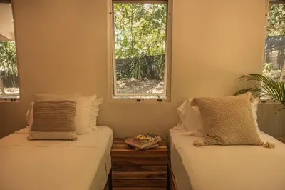 two beds in a room with two windows at Arroyo Tranquilo - Steps to the Beach in Santa Teresa Beach